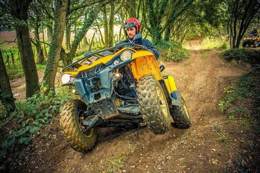Un quad colorato giallo su un sentiero sterrato, circondato da alberi. 2