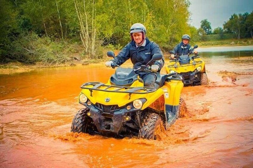 Due persone guidano veicoli fuoristrada gialli attraverso una zona allagata con acqua fangosa. 1