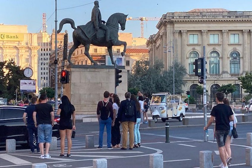 A busy intersection with a statue of a man on a horse, traffic lights, and a building with a dome. 2