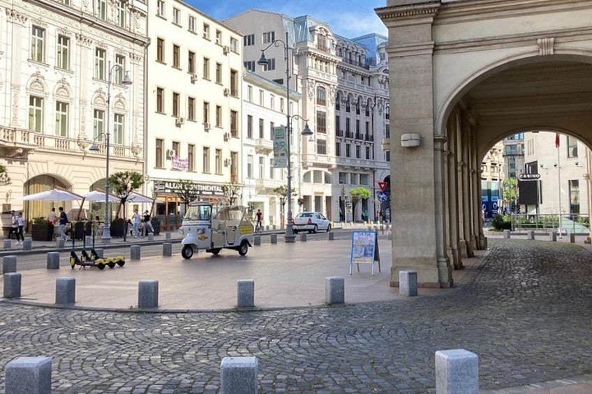 A cobblestone street, a vintage car, and historic buildings. 2
