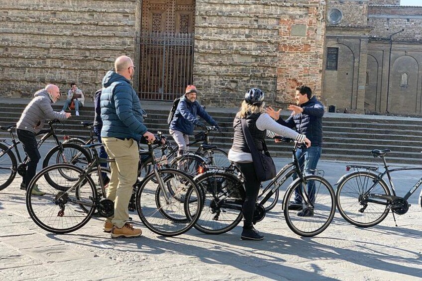 A group of people with bicycles in front of a stone building. 3