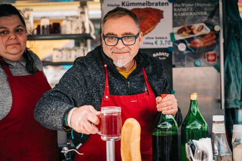 Eine Person in einer roten Schürze gießt Flüssigkeit aus einer Flasche in ein Glas. 5