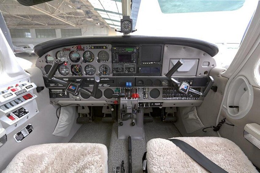 An aircraft cockpit with multiple gauges, a control panel, and two seats. 3