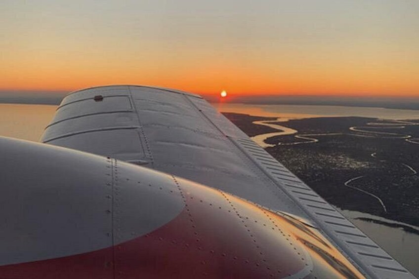 Une aile d’avion, un coucher de soleil et une étendue d’eau. 5