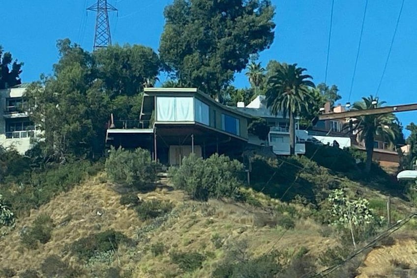 Een glooiend landschap met een huis, bomen en een elektriciteitspaal. 3