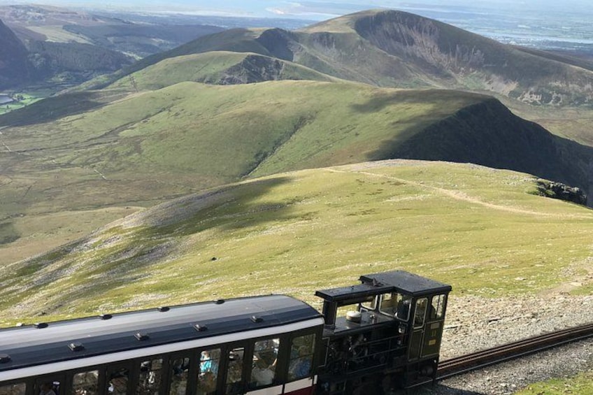 Un train circule sur des voies ferrées, avec un paysage montagneux en arrière-plan. 5