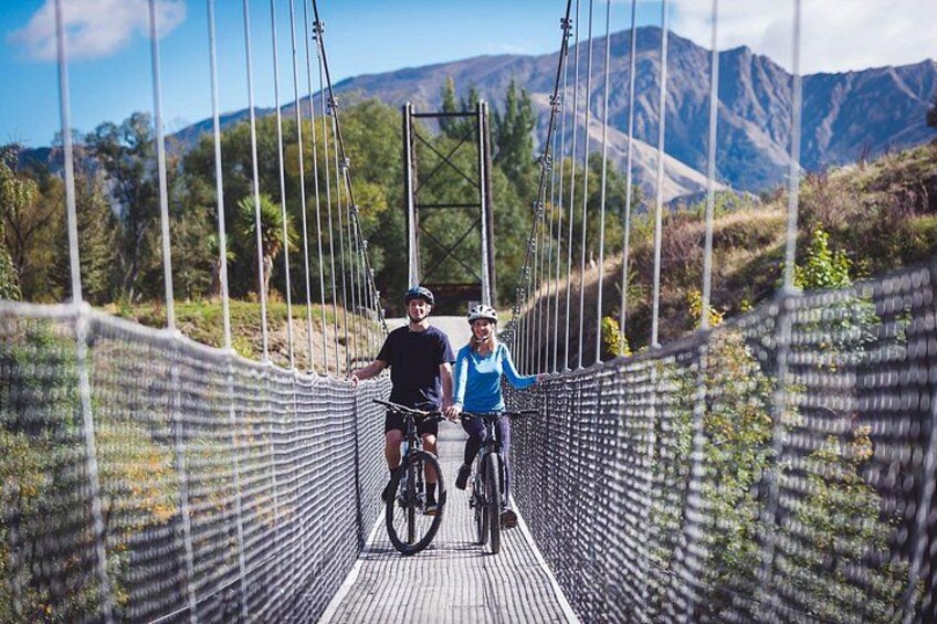 Due persone su un ponte sospeso con montagne sullo sfondo. 1