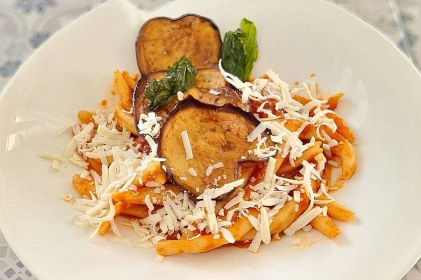 Un plato de pasta con rodajas de berenjena y queso rallado. 1