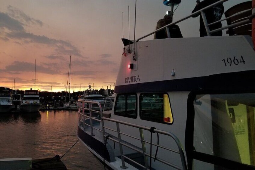 A boat named RIVIERA docked at a marina with other boats in the background during sunset. 5