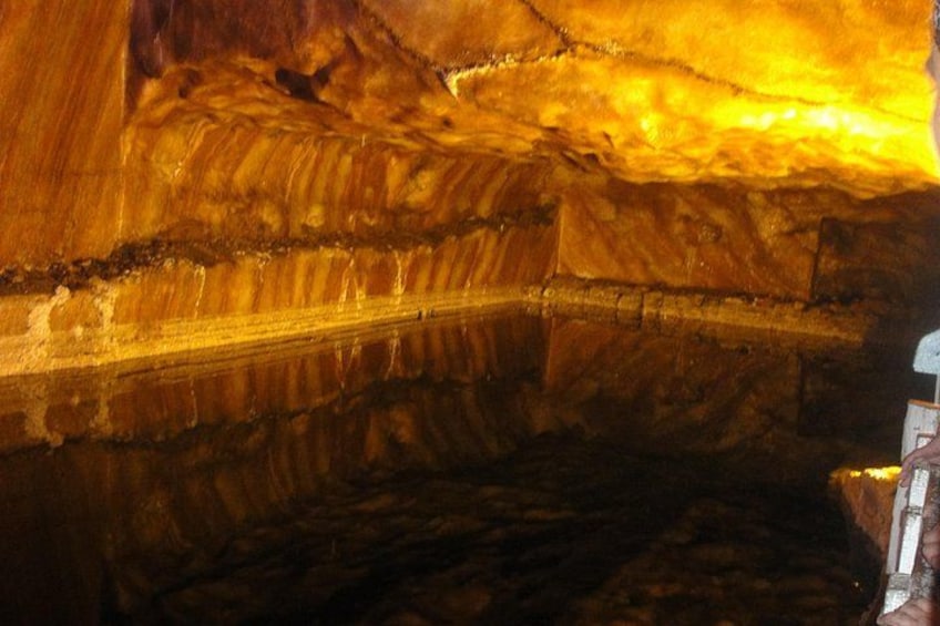 Interior de una cueva con estalactitas y una mano sosteniendo una linterna. 2