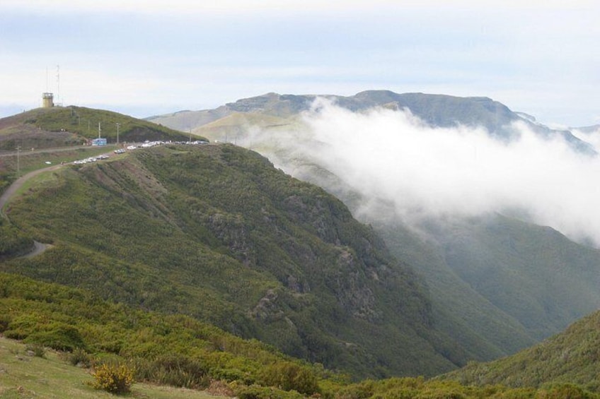 A mountainous landscape with a road winding through it, surrounded by lush greenery and clouds. 5