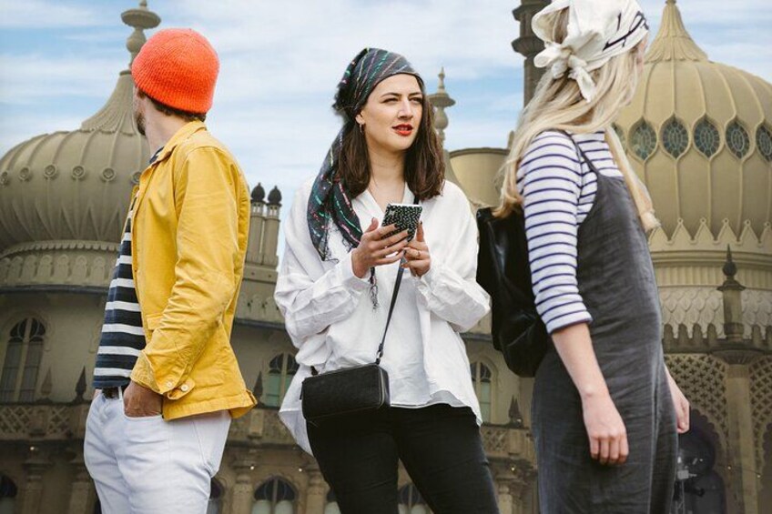 Three people walking in front of a historic building with domed architecture. 1
