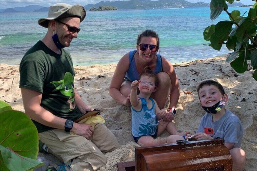 En familie på en sandstrand med kig til havet og fjerne øer. 2