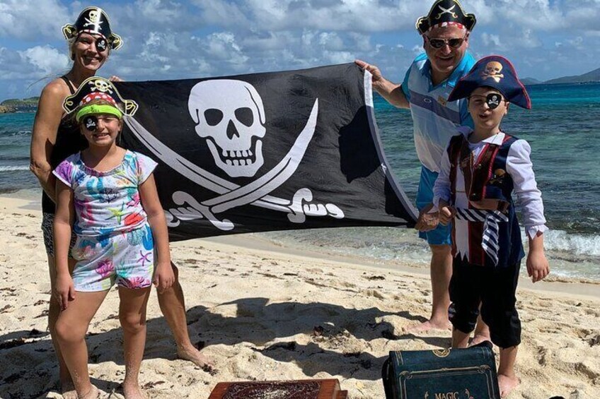 Tre personer på en strand med et piratflag. 1