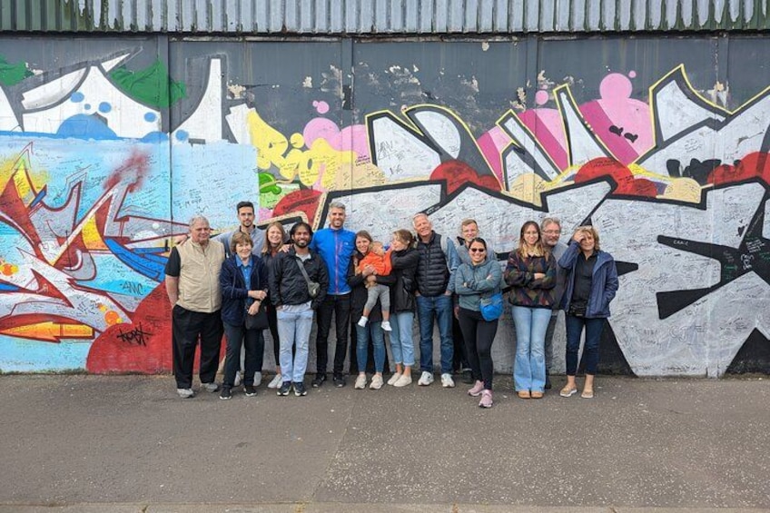 Un grupo de personas frente a un muro lleno de grafitis coloridos. 1