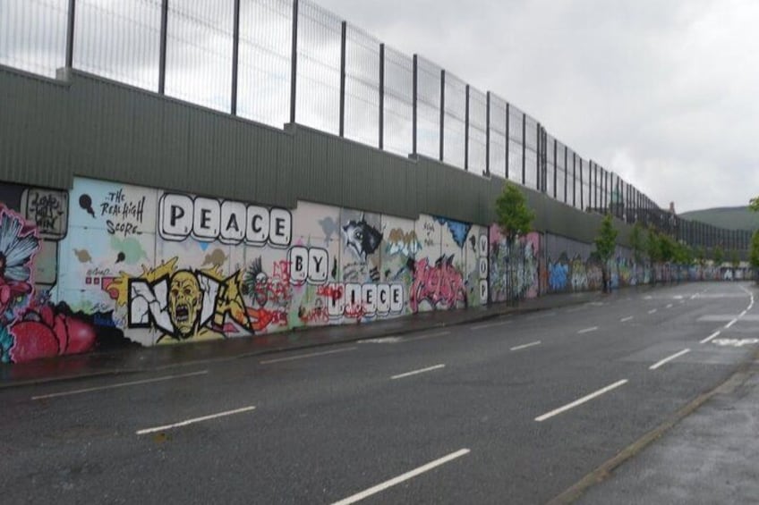 Una calle con un muro lleno de grafitis y una cerca. 2