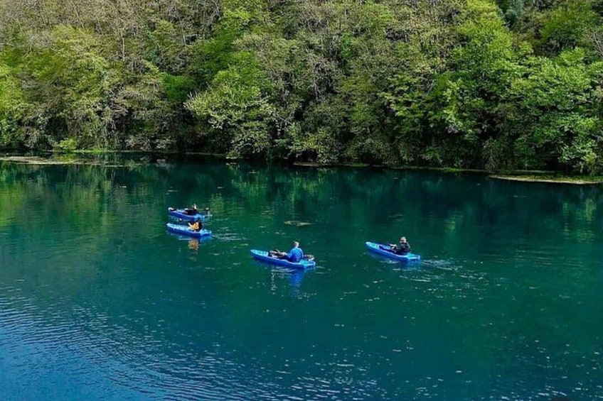 Three kayaks on a calm river surrounded by dense greenery. 4