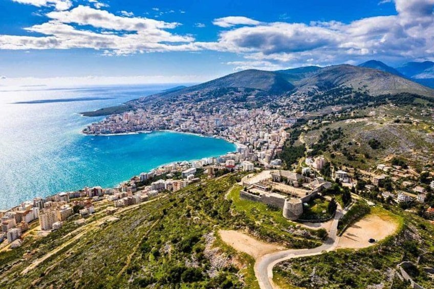 A coastal city with a prominent ancient fortress, a winding road, and a large body of water. 2