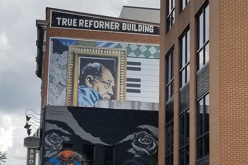 Un edificio con un murale raffigurante un uomo e rose, e il testo 'TRUE REFORMER BUILDING'. 2