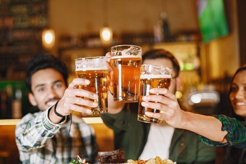 A group of people toasting with beer glasses at a bar. 3