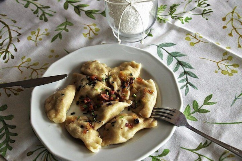 A plate of ravioli with a creamy sauce and garnished with herbs and bacon bits. 2