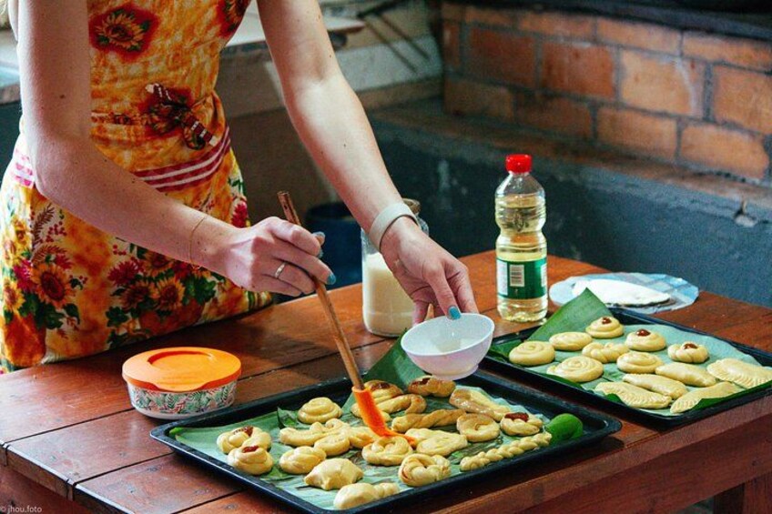 Una persona preparando comida con un bol, una botella y una bandeja de pasteles sobre una mesa de madera. 1