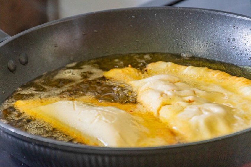 A frying pan with oil and a food item being cooked. 5