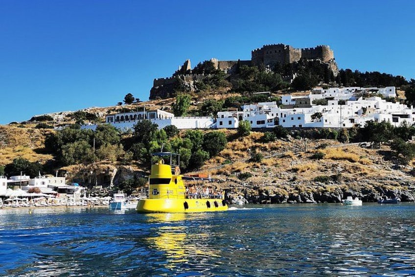Une ville côtière aux bâtiments blancs, avec un bateau jaune et un château perché sur une colline. 3