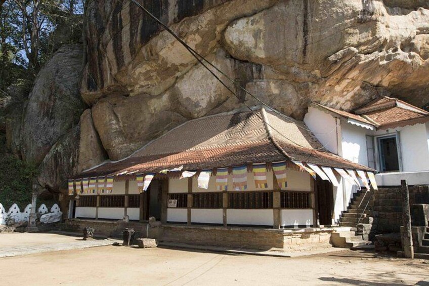 Un bâtiment traditionnel, doté d’un toit en tuiles, situé devant une grande formation rocheuse. 2