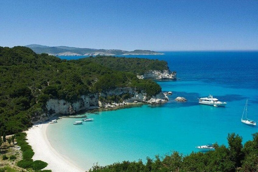 A coastal landscape with a beach, clear turquoise waters, boats, and lush greenery. 2