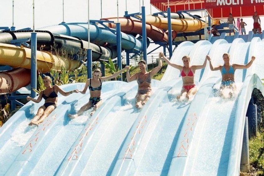 Uno scivolo acquatico con diverse corsie e persone che vi scivolano giù. 1