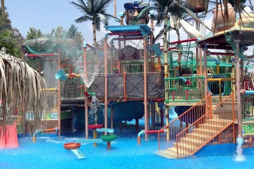 Un parco acquatico con scivoli, piscina a onde e un solarium in legno. 2