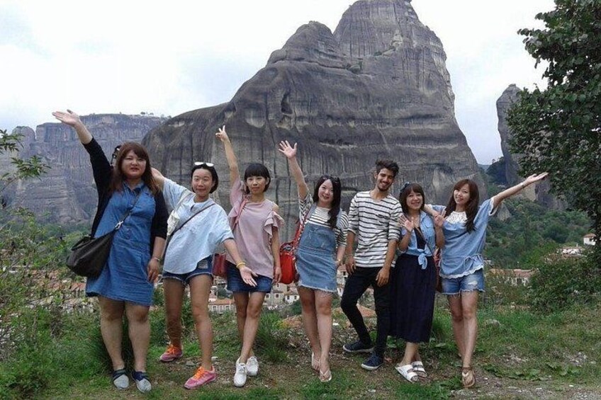 A group of people posing in front of a large rock formation. 2