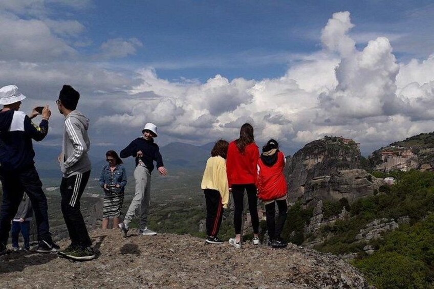 A group of people standing on a rocky outcrop overlooking a valley with a mountain in the background. 3