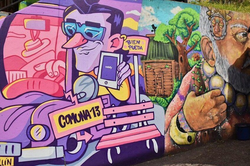 Un mural con un personaje sosteniendo un cartel que dice 'COMUNA 13' y un teléfono inteligente. 4