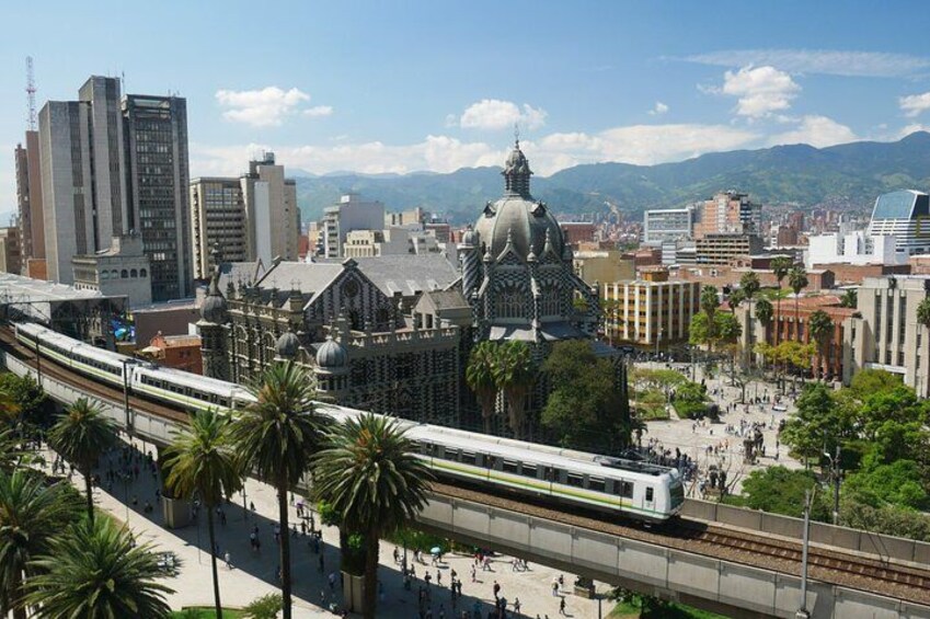Un tren sobre rieles, un edificio grande con cúpula y un paisaje urbano con montañas al fondo. 5