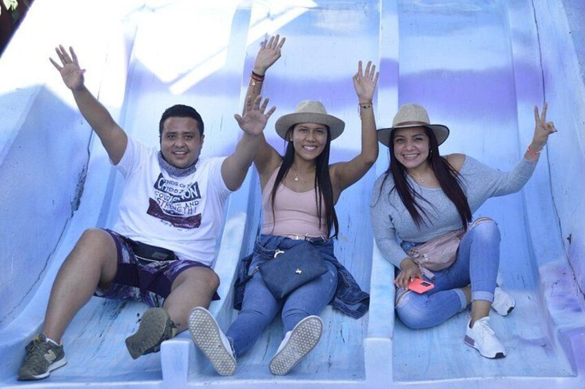 Tres personas resbalando por un tobogán azul. 2