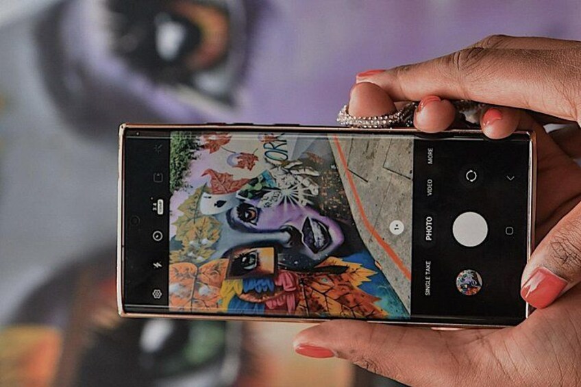 Una persona sostiene un teléfono inteligente con una cámara mostrando un colorido mural. 4