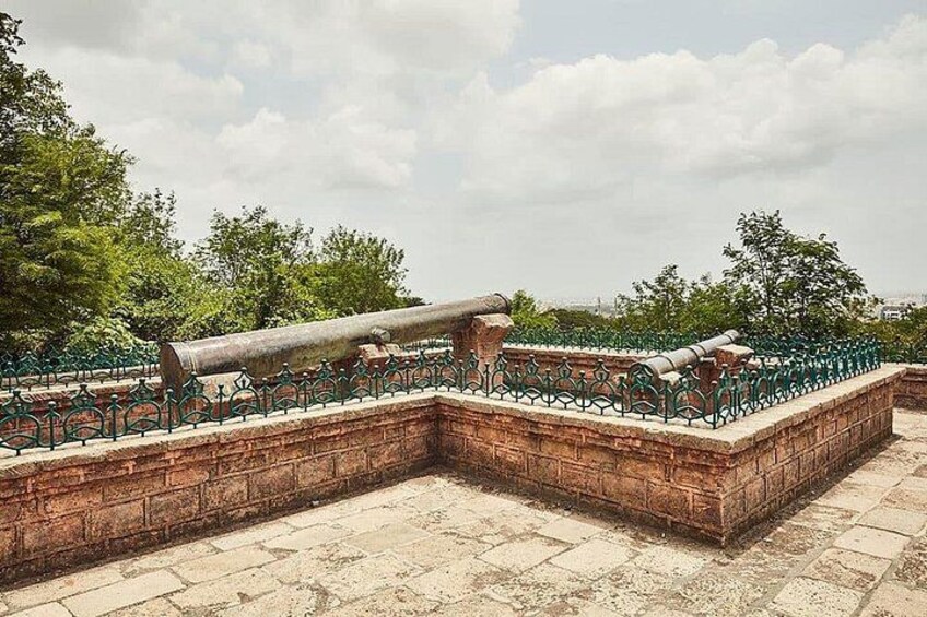 A historical fortification with cannons, brick walls, and green metal railings. 2