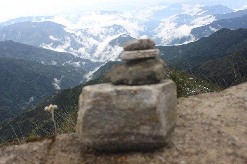 A stack of stones on a mountain with a view of distant mountains and clouds. 2