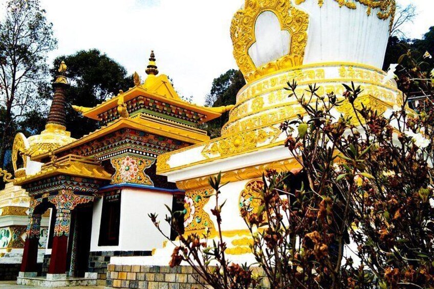 A temple with intricate golden and white decorations, a large central dome, and a smaller structure with a red roof. 2