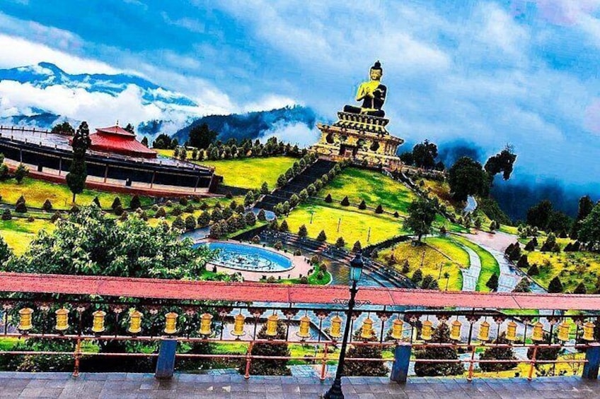 A large Buddha statue on a hill, surrounded by a landscaped garden with a pool. 3