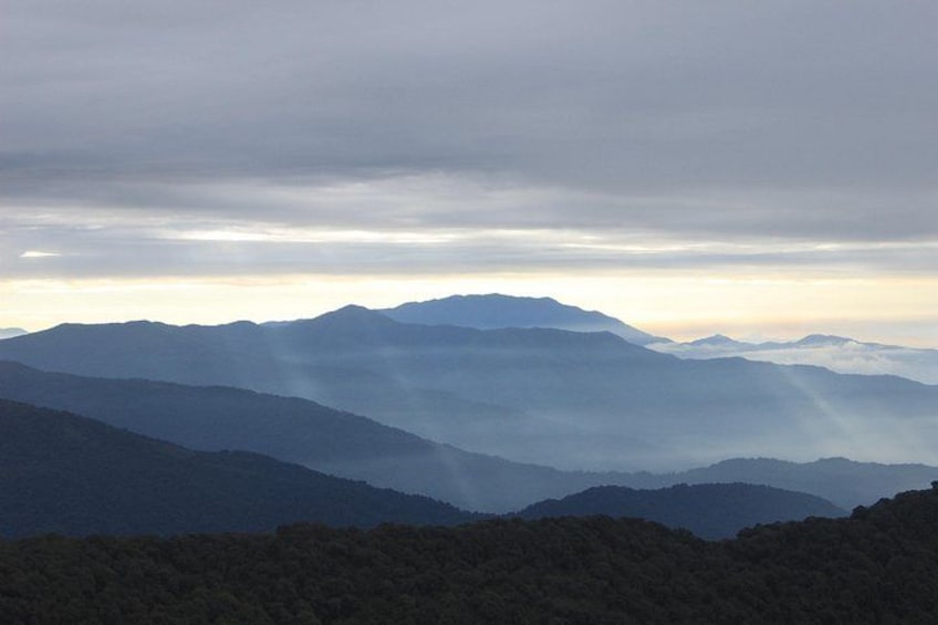A mountain range with layered peaks and a cloudy sky. 1