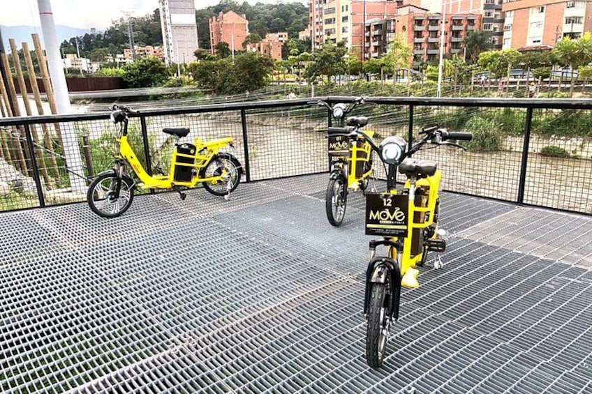 Two yellow electric scooters parked on a metal platform with a cityscape in the background. 5