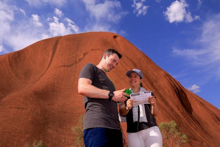 Two people standing in front of a large red rock formation with a clear sky in the background. 5