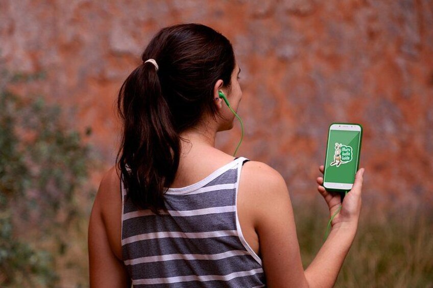 A person holding a smartphone with a green app icon, wearing a striped tank top, and earphones. 4