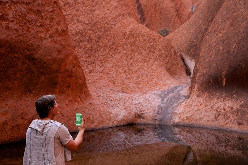 A person taking a photo of a red rock canyon with a narrow path. 3