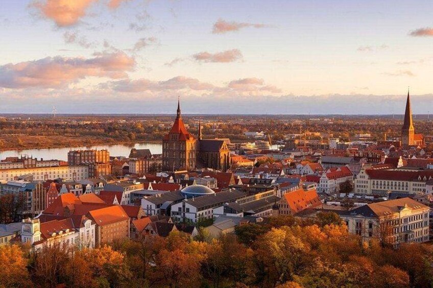 A cityscape with prominent church spires, a river, and autumn foliage. 4