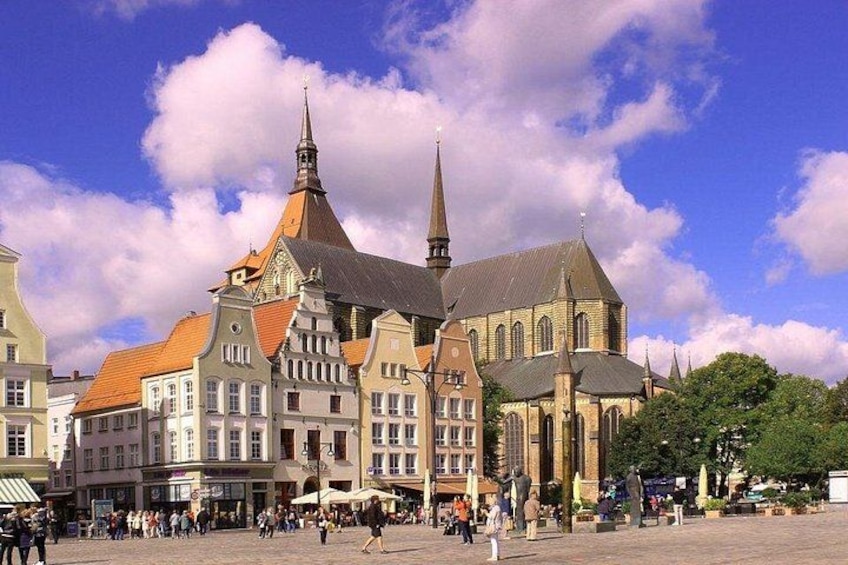 A historic town square with a prominent church featuring a tall spire and a variety of traditional buildings. 5