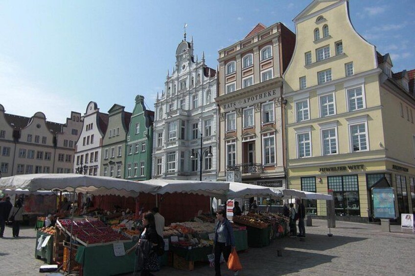 A European market with stalls and historic buildings in the background. 1